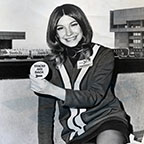 Passenger service representative holding a button, 1970s.